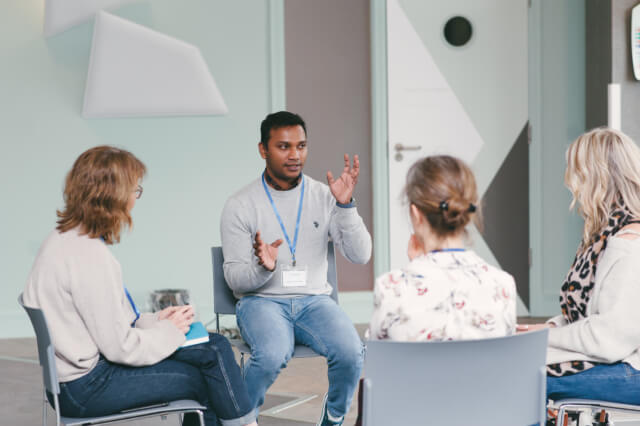 A group of four colleagues sat on chairs in a circle having a discussion